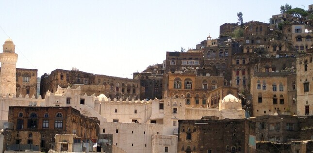 Vue d’une ville ancienne aux maisons en pierre empilées sur une colline, avec une architecture traditionnelle.