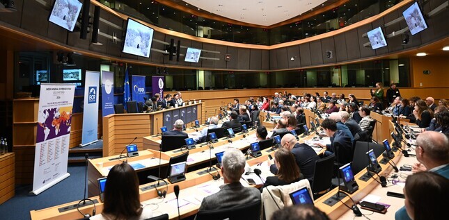 Des participants assistent à une conférence dans une grande salle institutionnelle, avec un écran et des panneaux présentant l’Index Mondial de Persécution des Chrétiens.