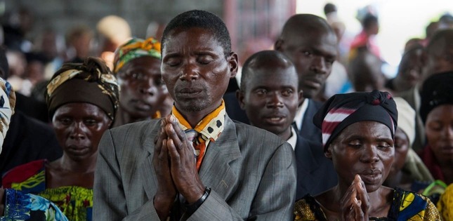 Des fidèles prient les yeux fermés lors d’un rassemblement dans une église.