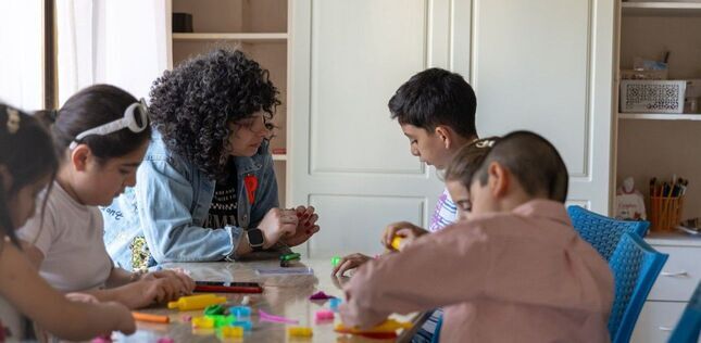 Vue d’une animatrice accompagnant un groupe d’enfants autour d’une activité créative.
