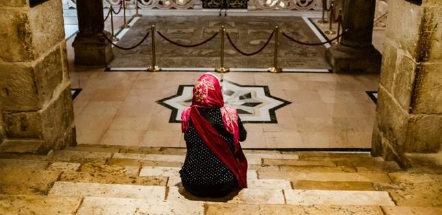 Vue d’une femme assise sur des marches à l’intérieur d’un édifice religieux.