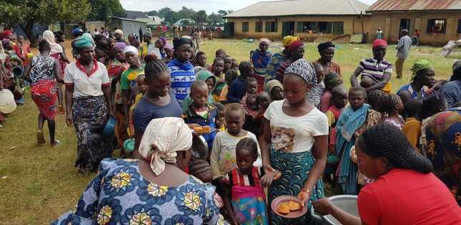 Vue de femmes et d'enfants faisant la queue pour recevoir une aide alimentaire dans un camp de déplacés au Nigéria.