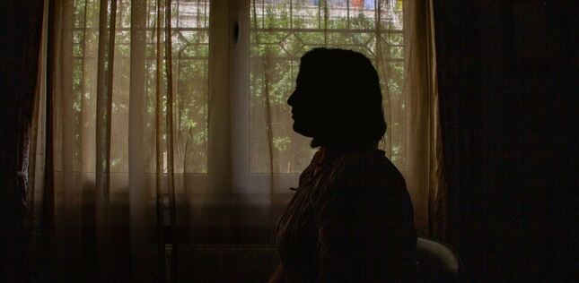Vue du profil d'une femme assise devant une fenêtre.