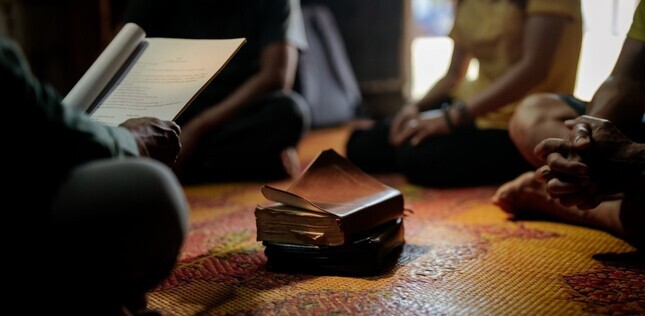 Vue de personnes assises en cercle, avec des livres au centre.