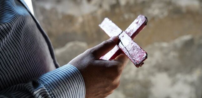 Vue rapprochée des mains d'une personne tenant une croix.