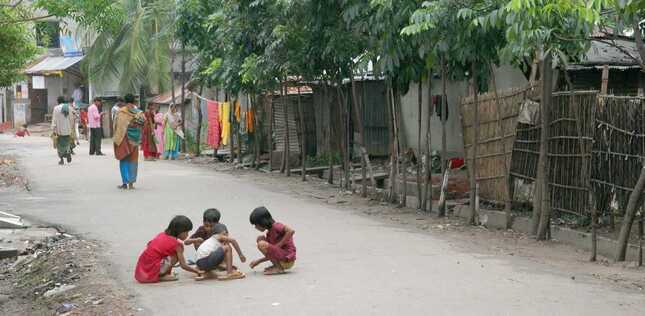 Vue de plusieurs enfants à l'extérieur, dans une rue bordée d'habitations.